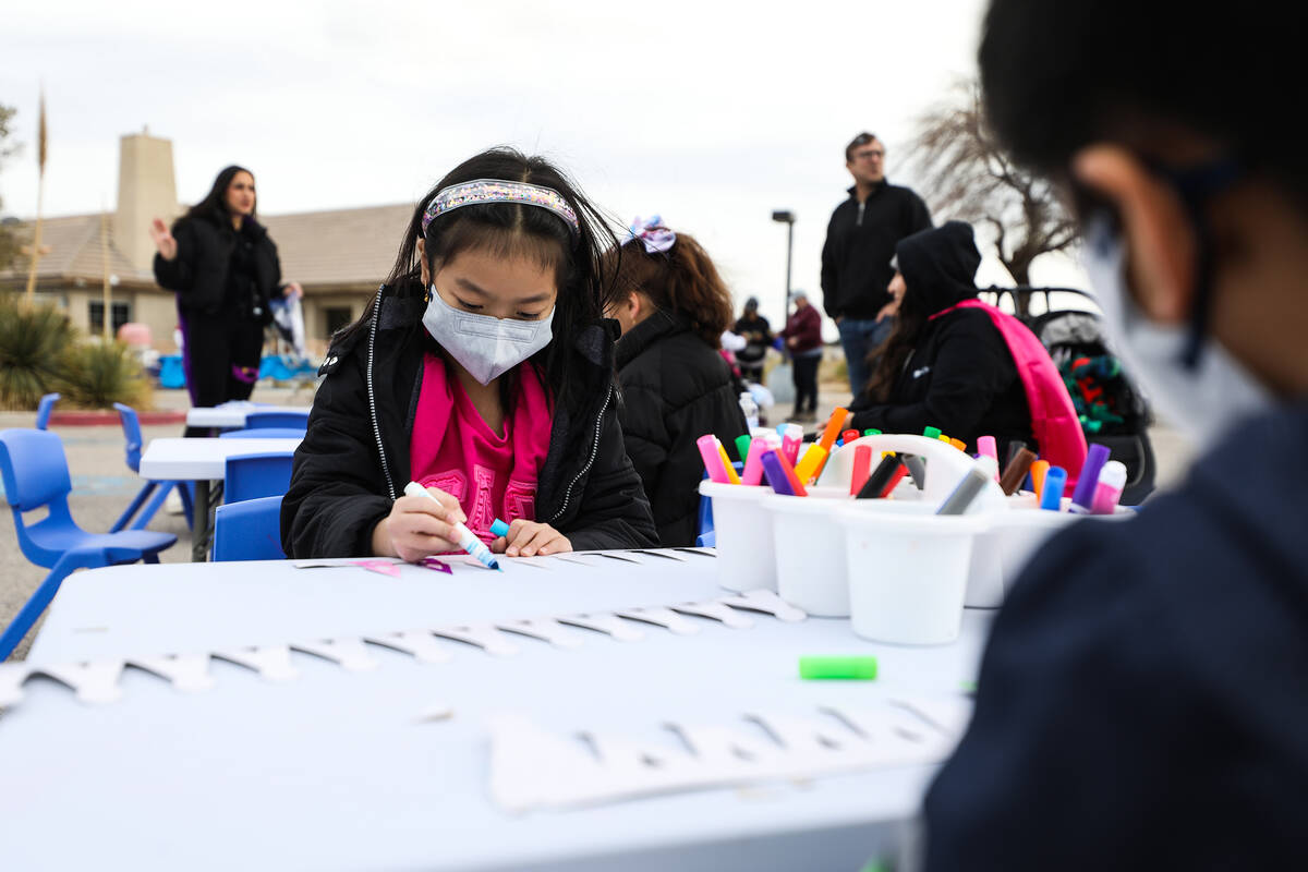 Jenell Canta, 8, colors a crown with her brother Jaxon Canta, 5, at a parade for the Jewish hol ...