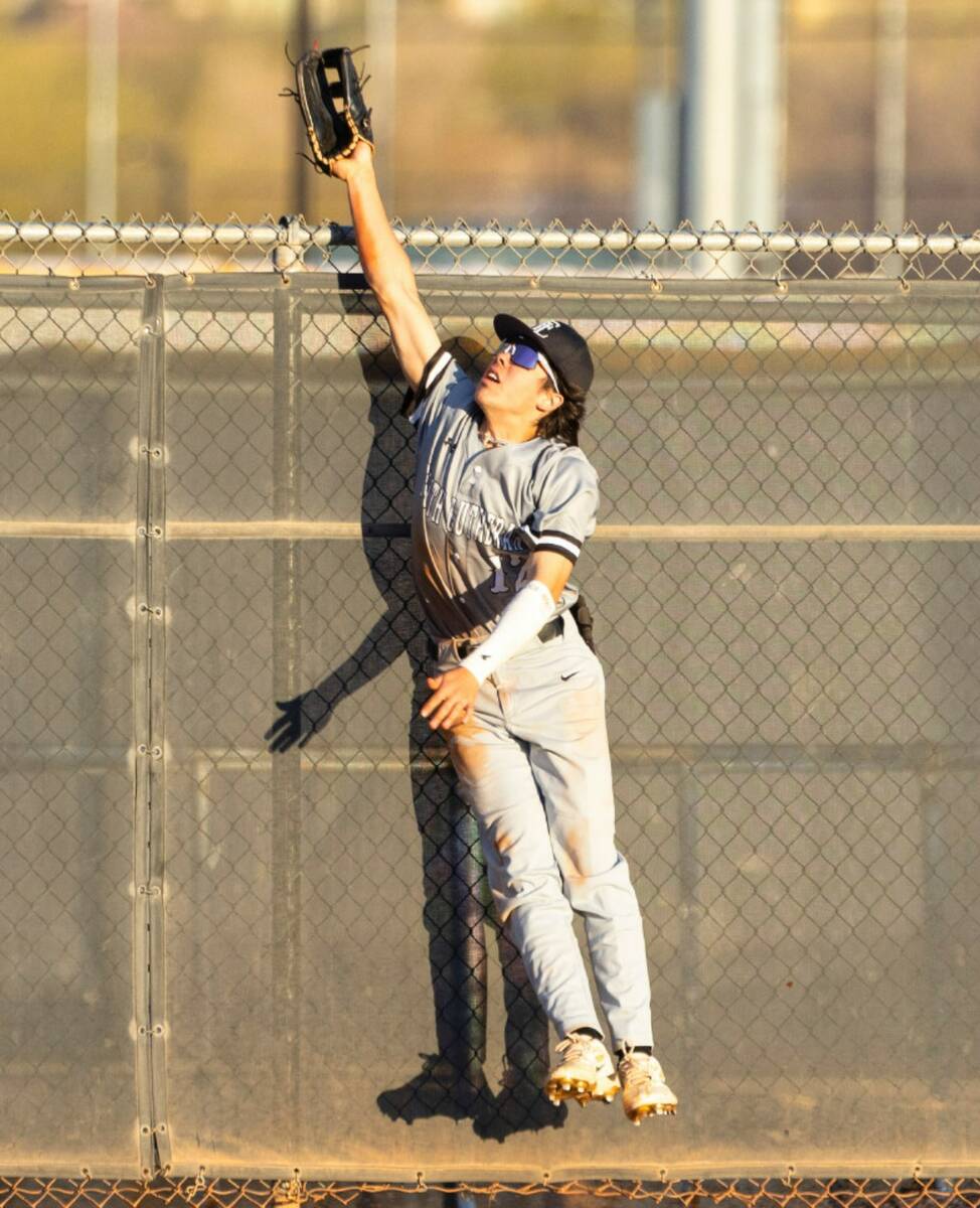 Faith Lutheran's Lucas Sideco jumps over the fence to catch a homer hit by Basic High's Tate So ...