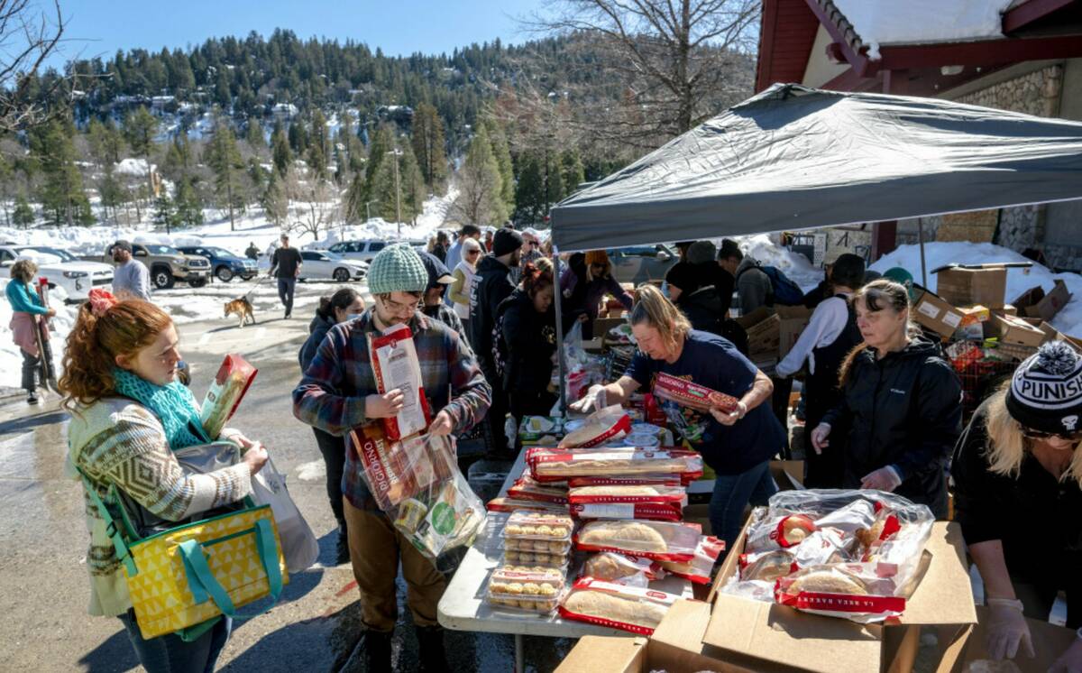 Crestline residents receive free food at a tent set up in front of the Goodwin & Son's Market i ...