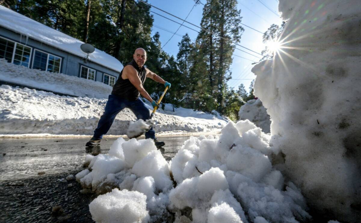 Michael Romero clears snow in front of his home, where his three vehicles are buried under heav ...