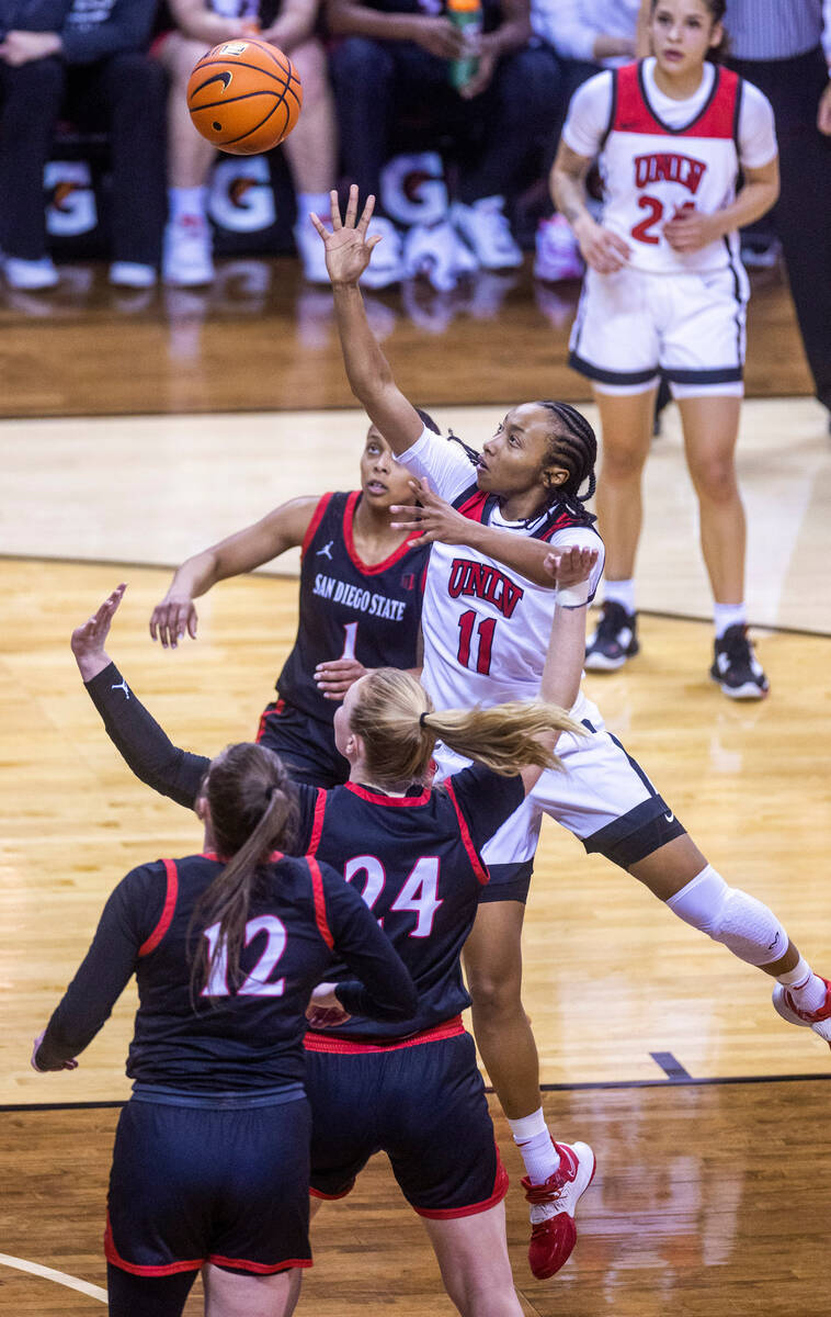 UNLV guard Justice Ethridge (11) gets off a shot over San Diego State guard Asia Avinger (1), g ...