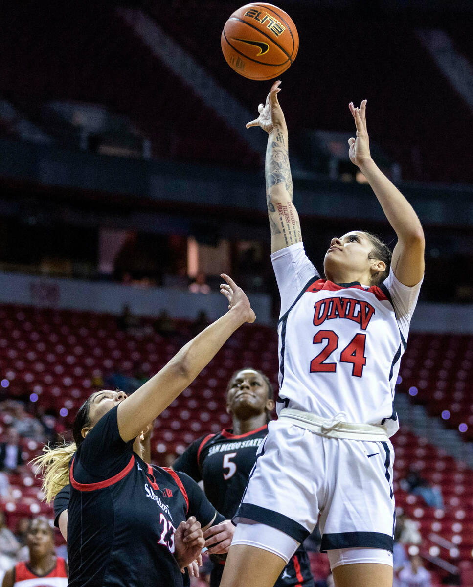 UNLV guard Essence Booker (24) gets in a late basket over San Diego State forward Kim Villalobo ...
