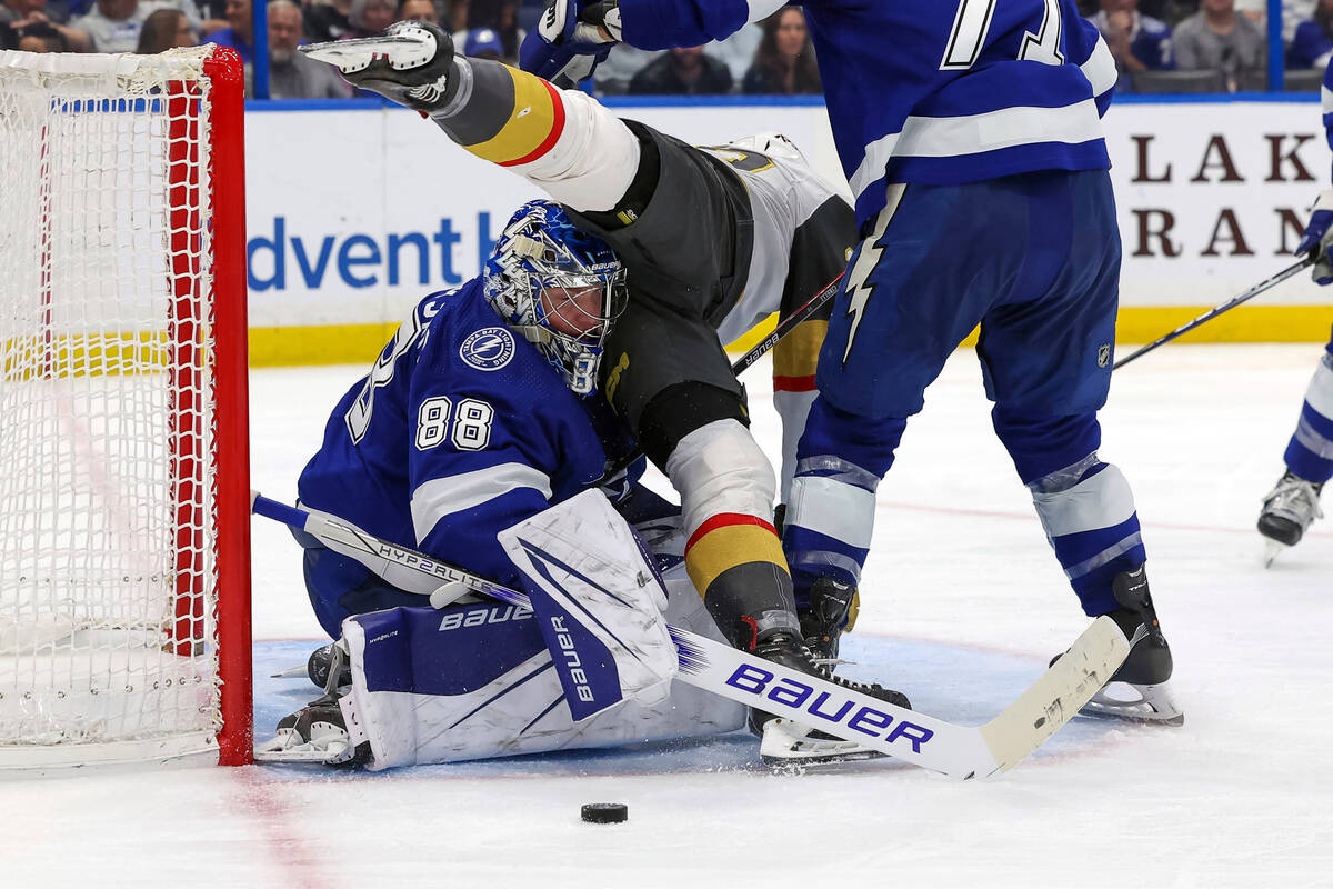 Vegas Golden Knights' Michael Amadio, center, collides with Tampa Bay Lightning goaltender Andr ...