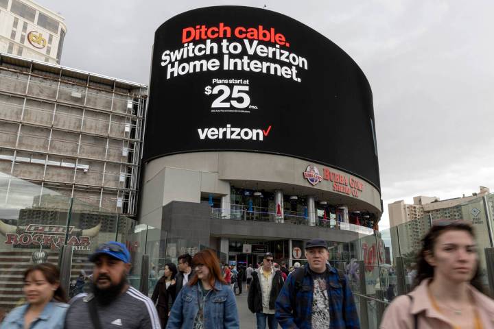 Pedestrians cross Las Vegas Boulevard with Harmon Corner, a retail complex at the intersection ...