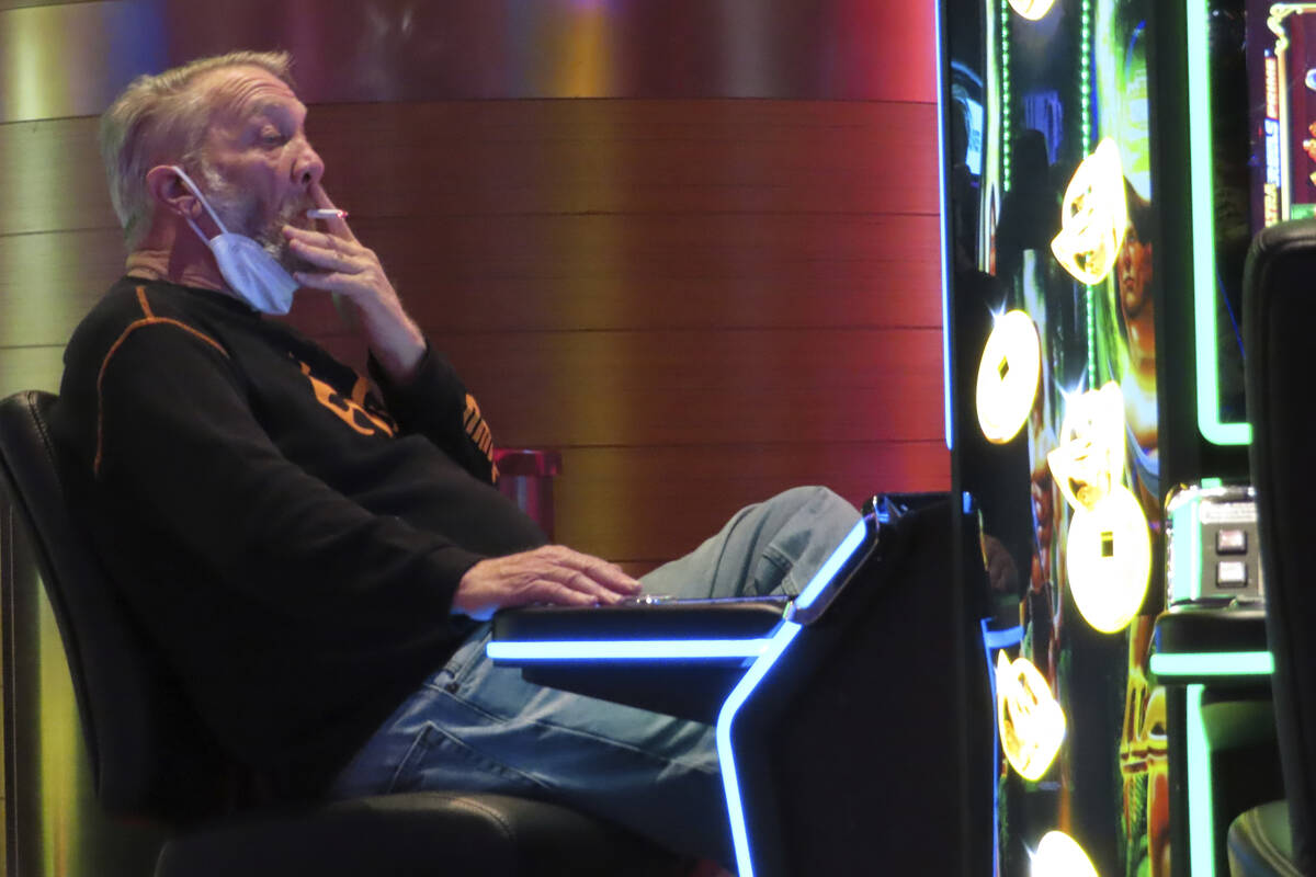 A gambler plays a slot machine while smoking in the Ocean Casino Resort in Atlantic City N.J. o ...