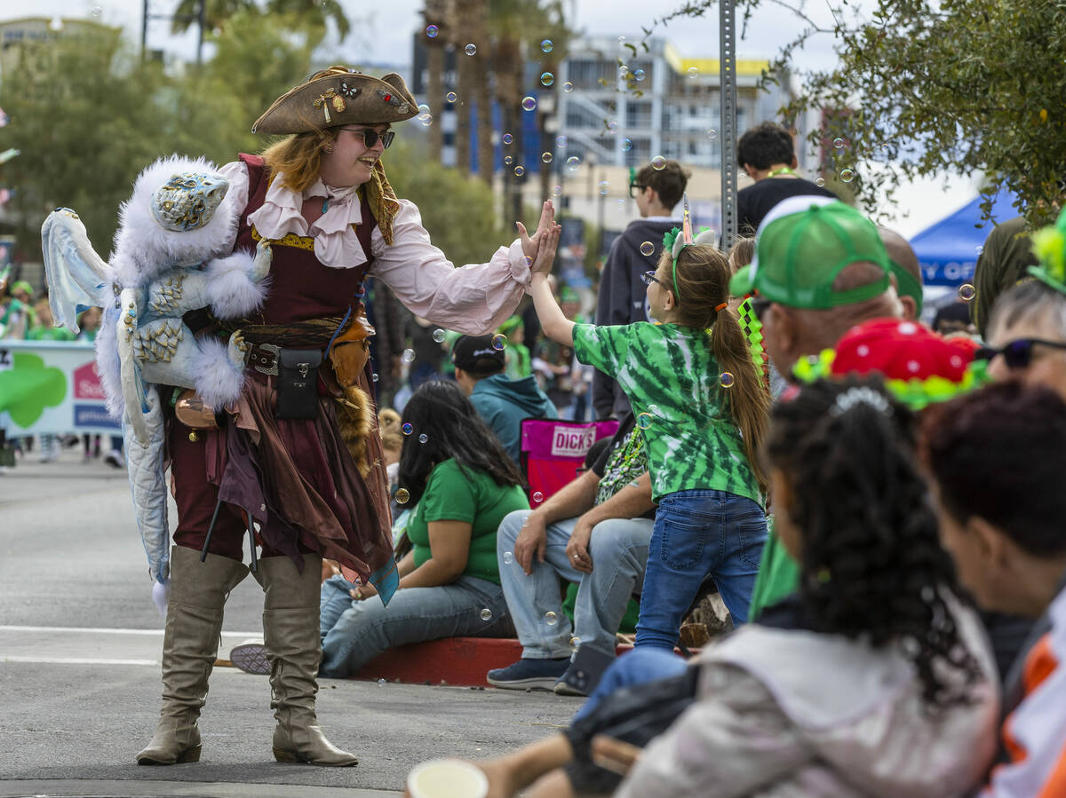 A pirate and her dragon greet a young attendee in the crowd along the parade route down Water S ...