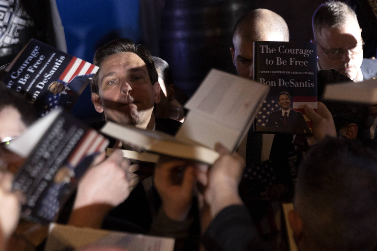 Florida Gov. Ron DeSantis reaches to sign copies of his book during a stop on his book tour at ...