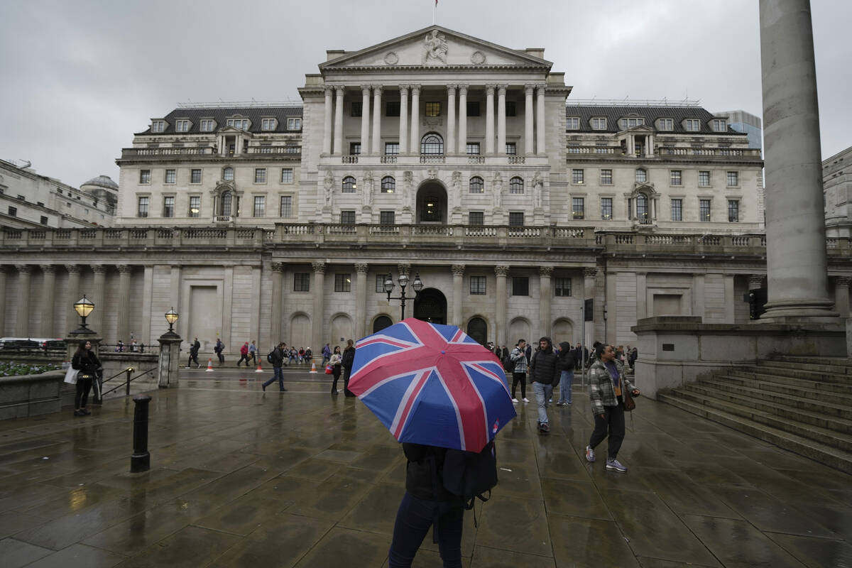 FILE - A woman with an umbrella stands in front of the Bank of England, at the financial distri ...
