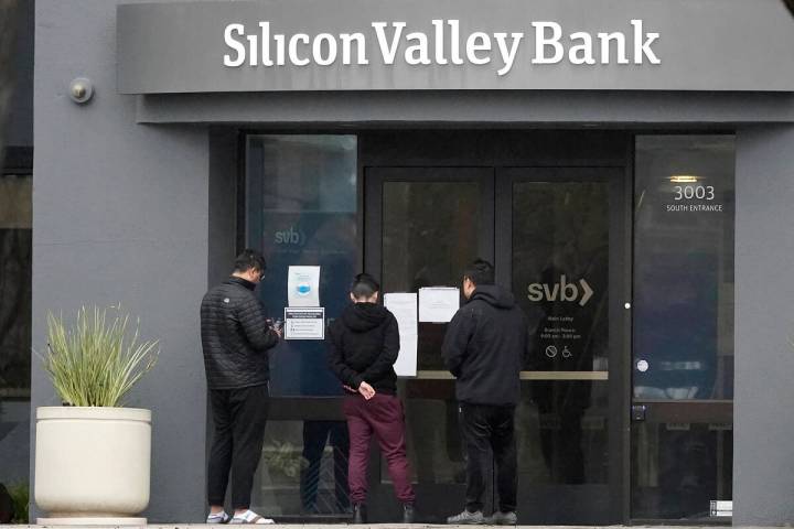 People look at signs posted outside of an entrance to Silicon Valley Bank in Santa Clara, Calif ...