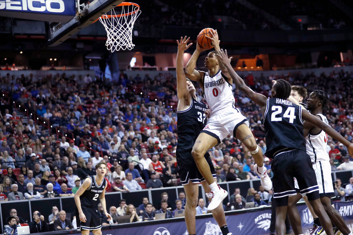 San Diego State forward Keshad Johnson (0) drives to the basket between Utah State center Trevi ...