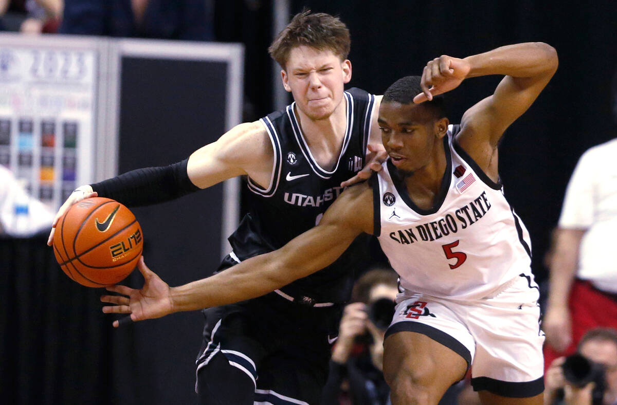 San Diego State guard Lamont Butler, right, tries to steal the ball from Utah State guard Max S ...