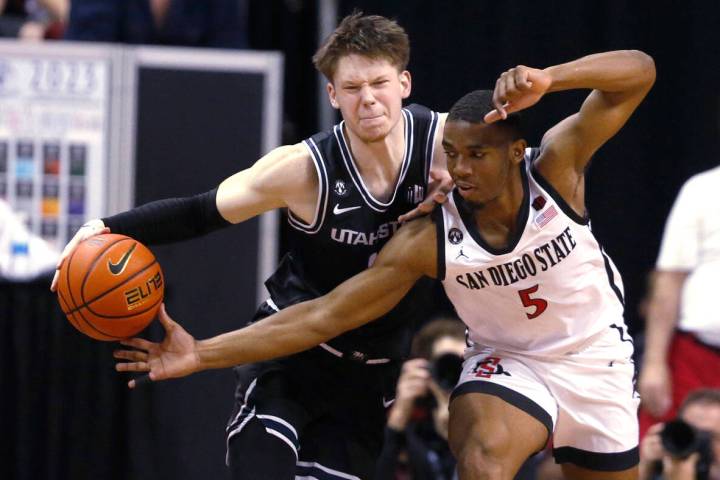 San Diego State guard Lamont Butler, right, tries to steal the ball from Utah State guard Max S ...