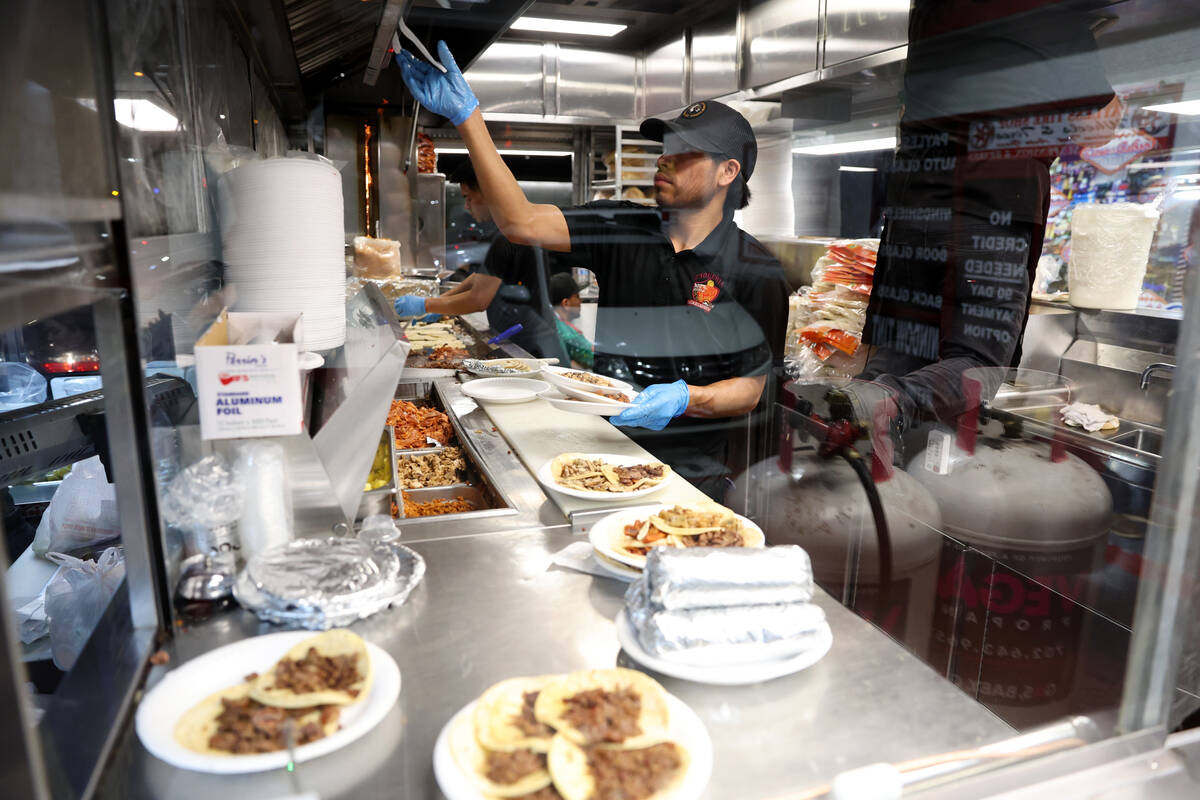 Staff members prepare food for customers during a buyout event in support of the taco street ve ...