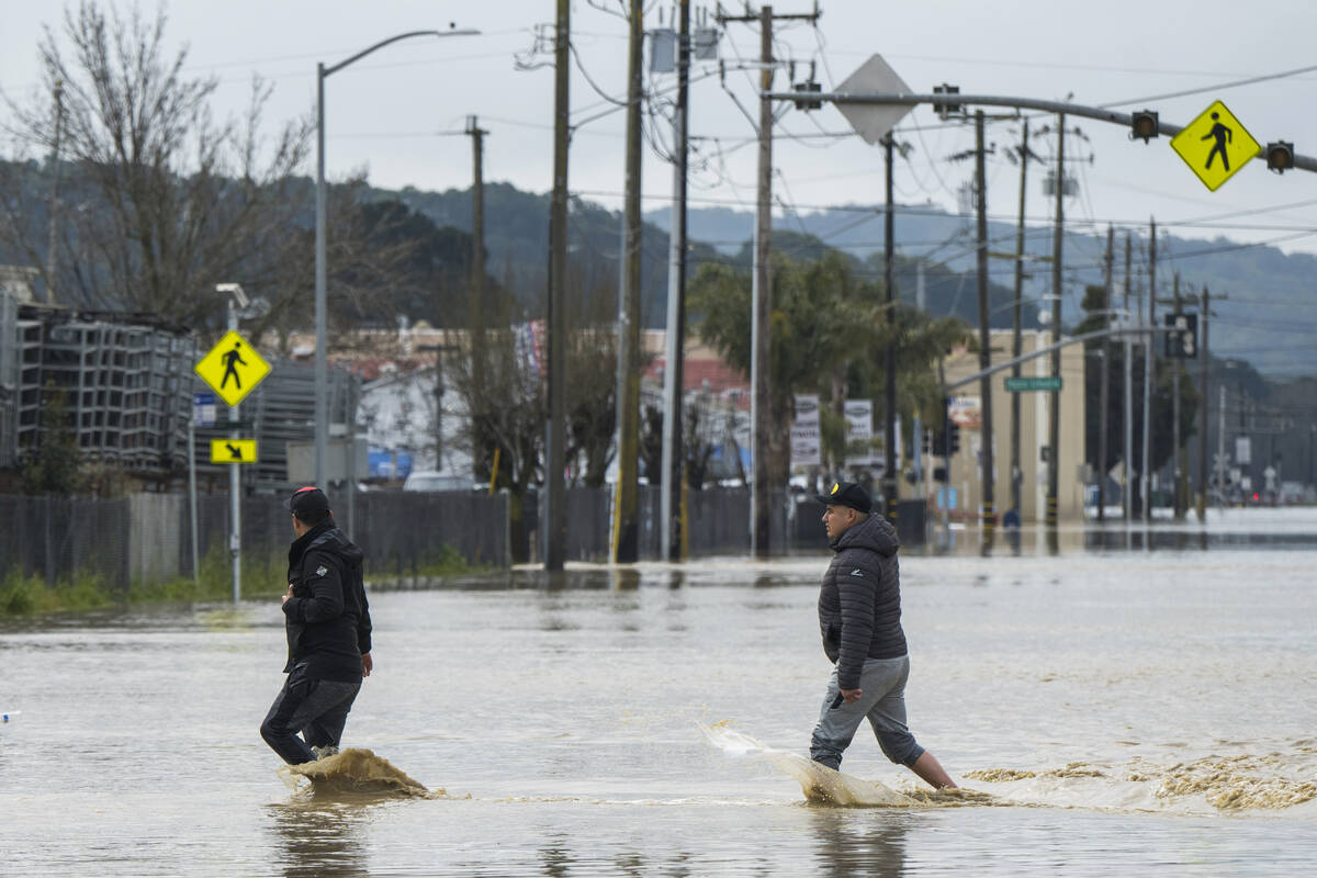 People walk through floodwaters in Watsonville, Calif., Saturday, March 11, 2023. Gov. Gavin N ...