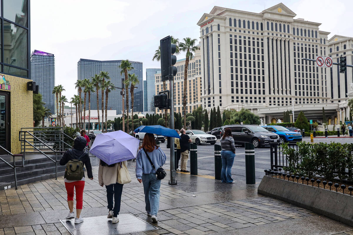 Pedestrians walk the Strip with umbrellas in Las Vegas, Tuesday, March 14, 2023. (Rachel Aston/ ...