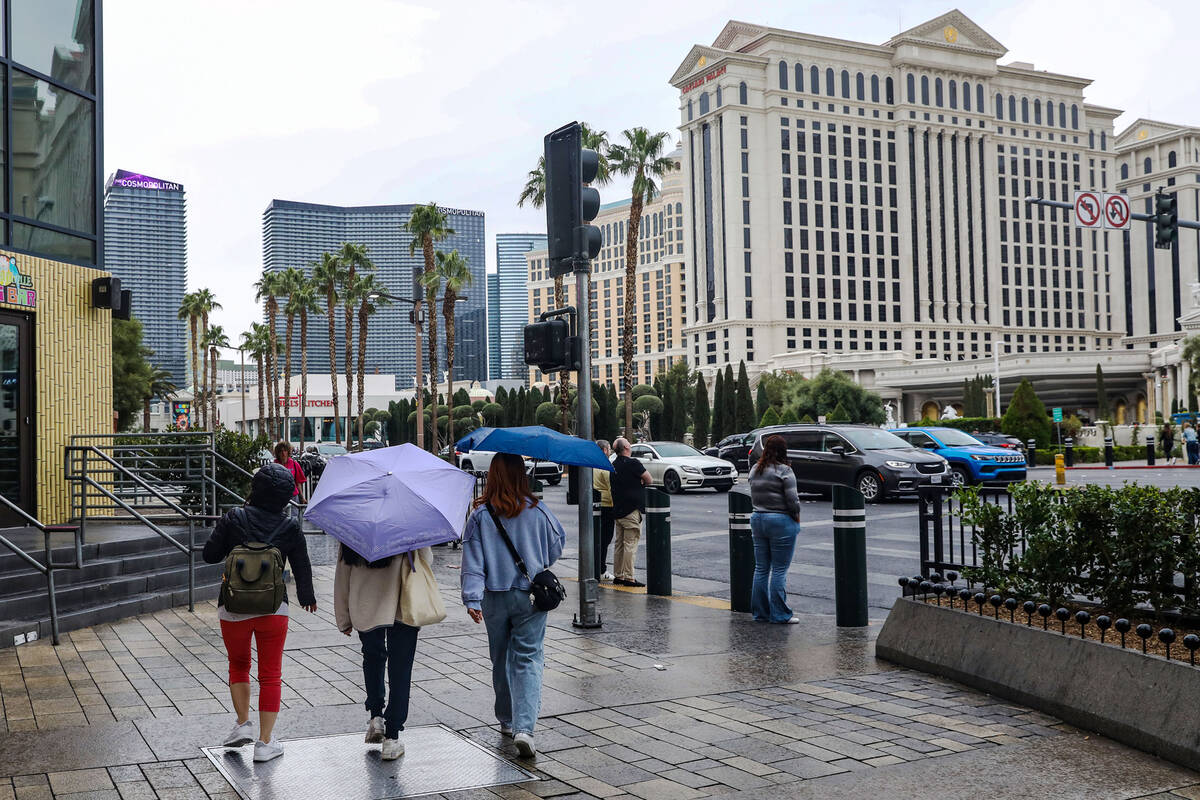 Pedestrians walk the Strip with umbrellas in Las Vegas, Tuesday, March 14, 2023. An incoming at ...