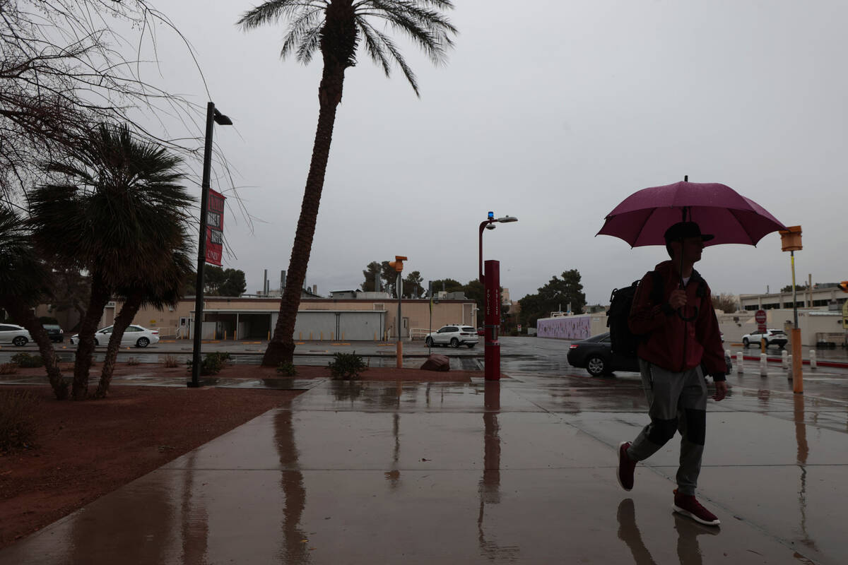 A man with an umbrella walks along the UNLV campus as rain comes down on Tuesday, March 14, 202 ...