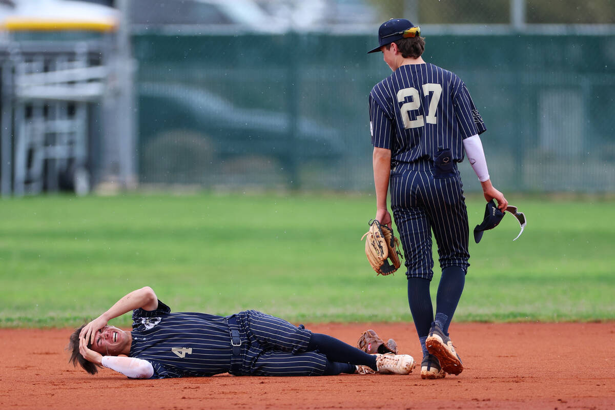 Spring Valley's Tyler Terk (4) lays on the ground as his teammate Grant Kelly (27) looks on, af ...