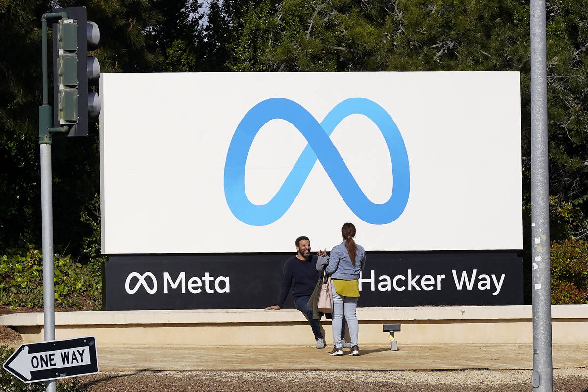 People talk near a Meta sign outside of the company's headquarters in Menlo Park, Calif., Tuesd ...