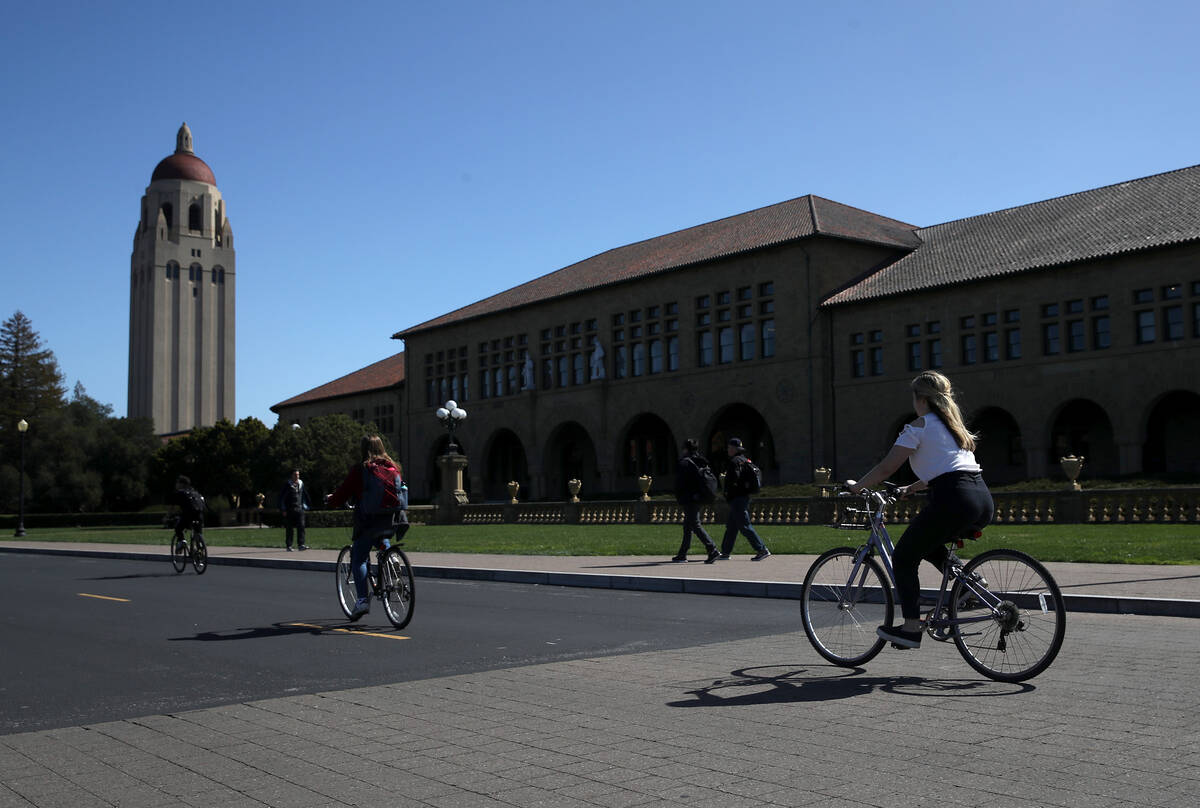 Cyclists ride by Hoover Tower on the Stanford University campus on March 12, 2019, in Stanford, ...