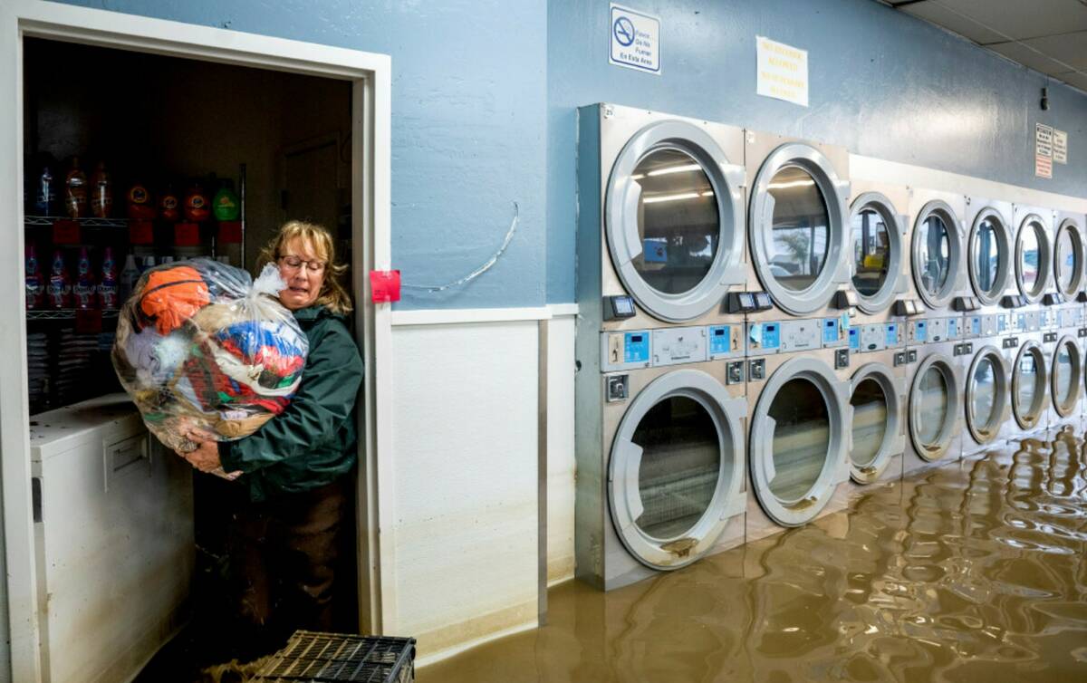 Pamela Cerruti carries clothing from Pajaro Coin Laundry as floodwaters surround machines in th ...