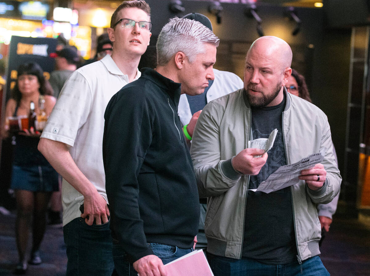 Guests line up to place bets during the first day of the NCAA basketball tournament at the West ...