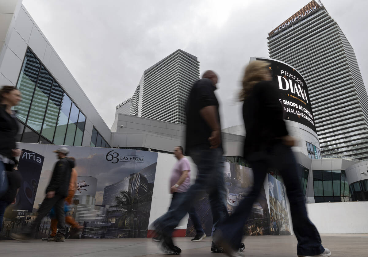 Pedestrians pass signs for 63, a new retail complex at the intersection of Las Vegas Boulevard ...