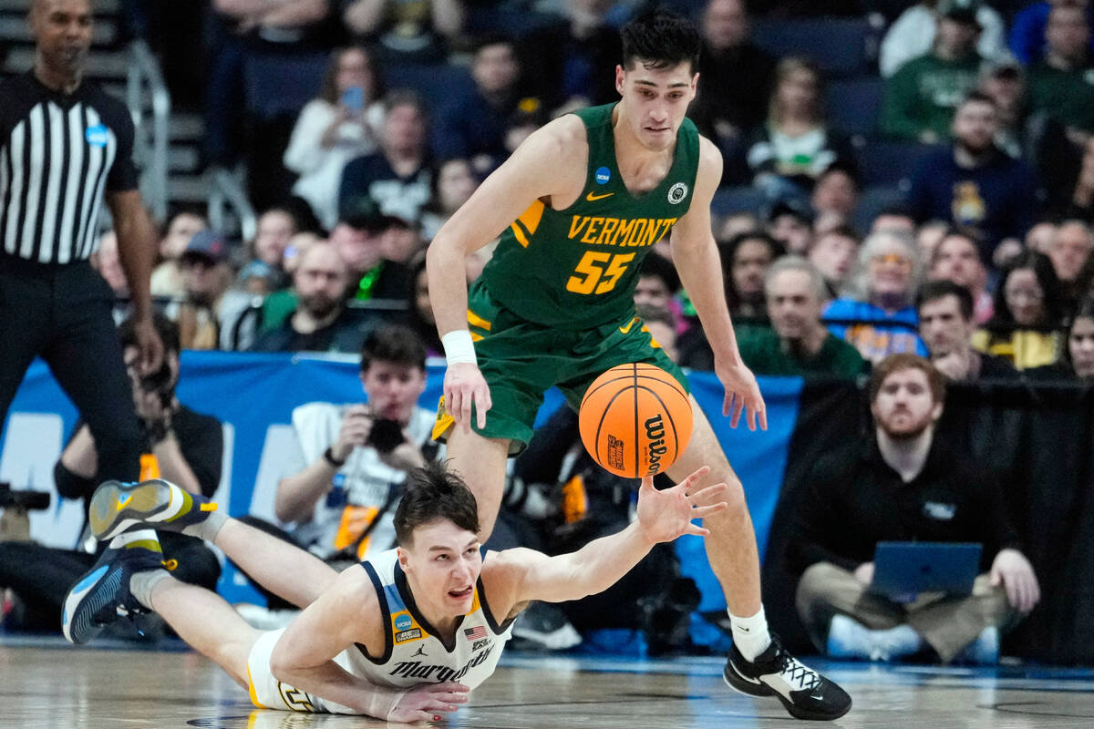 Marquette guard Tyler Kolek (11) dives for a loose ball in front of Vermont guard Robin Duncan ...