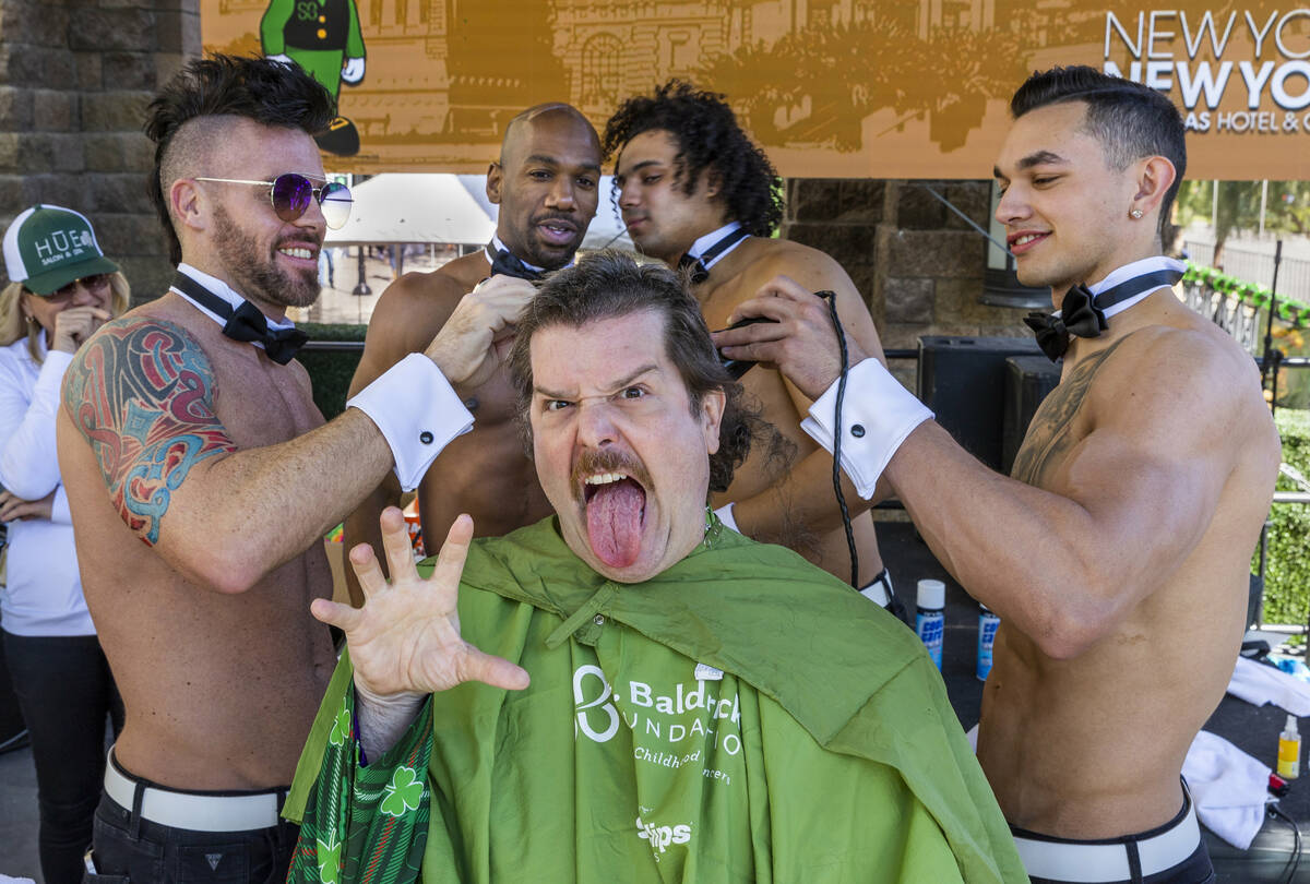 Celebrity Shaver Enoch Augustus Scott of Zombie Burlesque, center, has his head shaved by membe ...