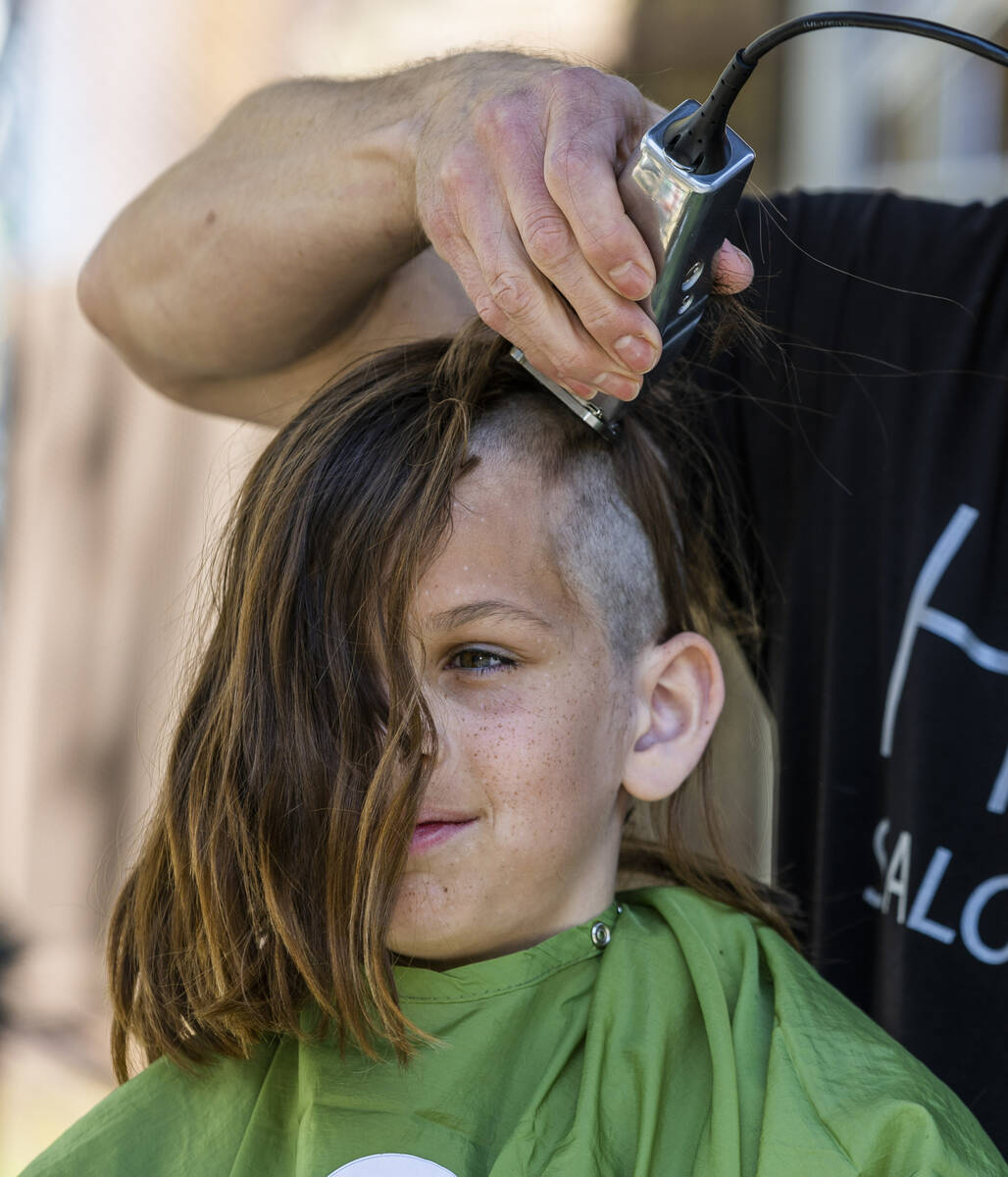 Henry Manjarres, 10, with a group from the Clark County Schools has his long hair shaved by a s ...