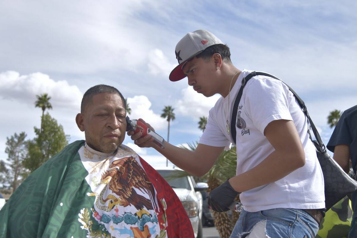 Jose Rodriguez, left, gets a haircut from Joshua Polo, right, on the sidewalk near Main Street ...