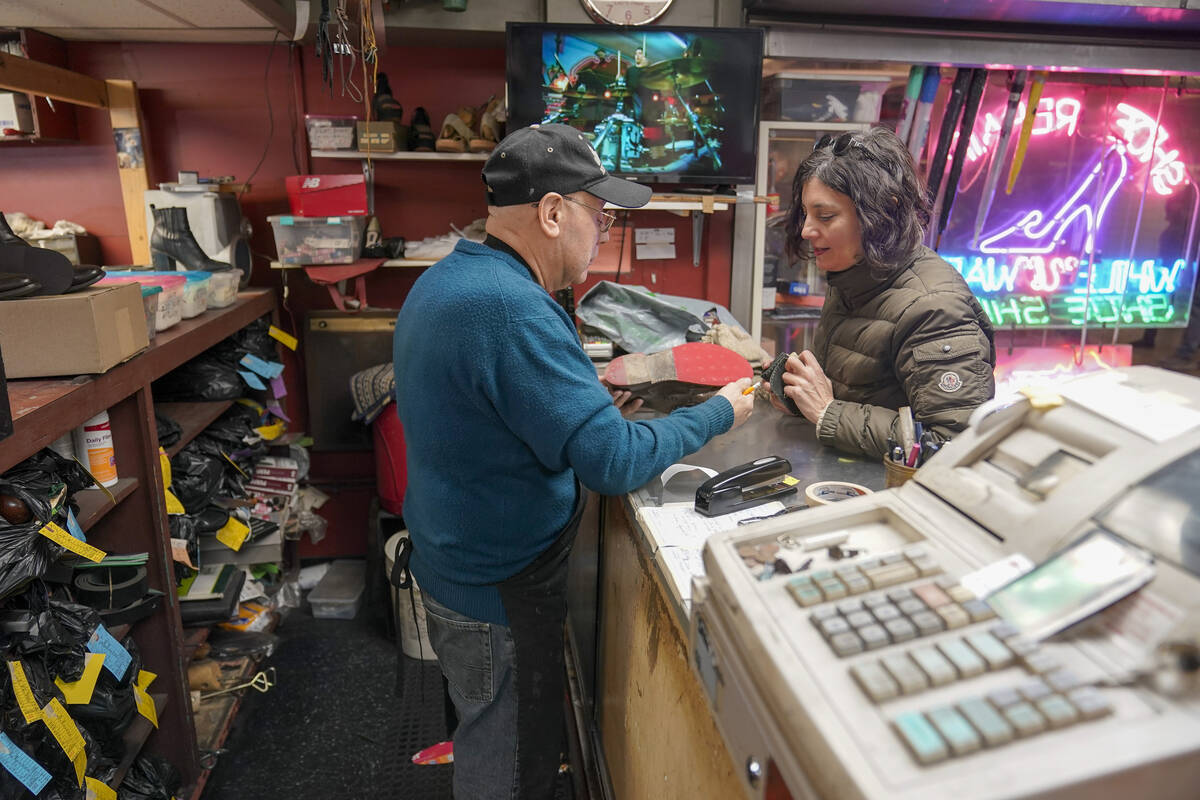 Jairo Cardenas, left, owner the Alpha Shoe Repair Corp., shows the repair made on a customer's ...