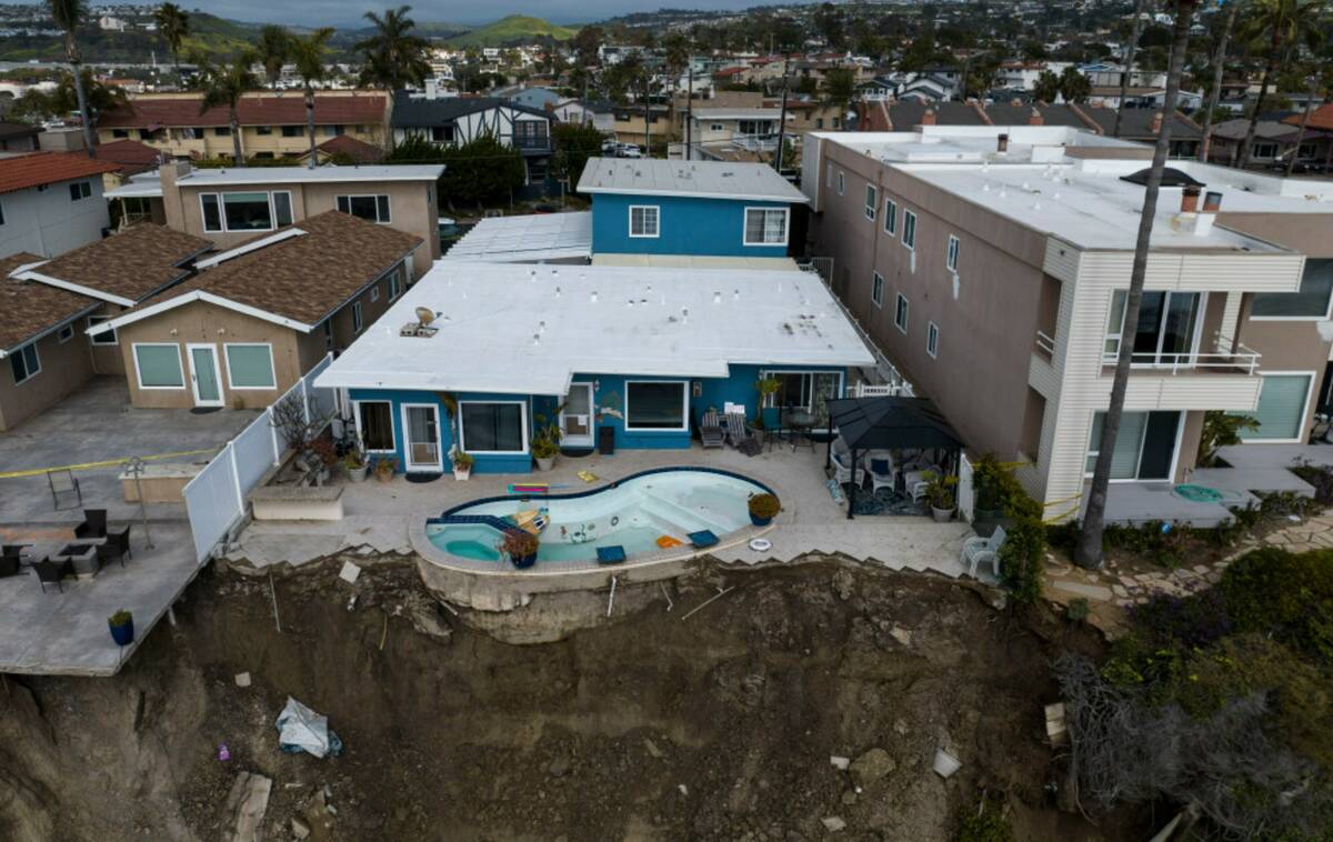 In this image taken with a drone, a residential swimming pool hangs on a cliffside after a land ...