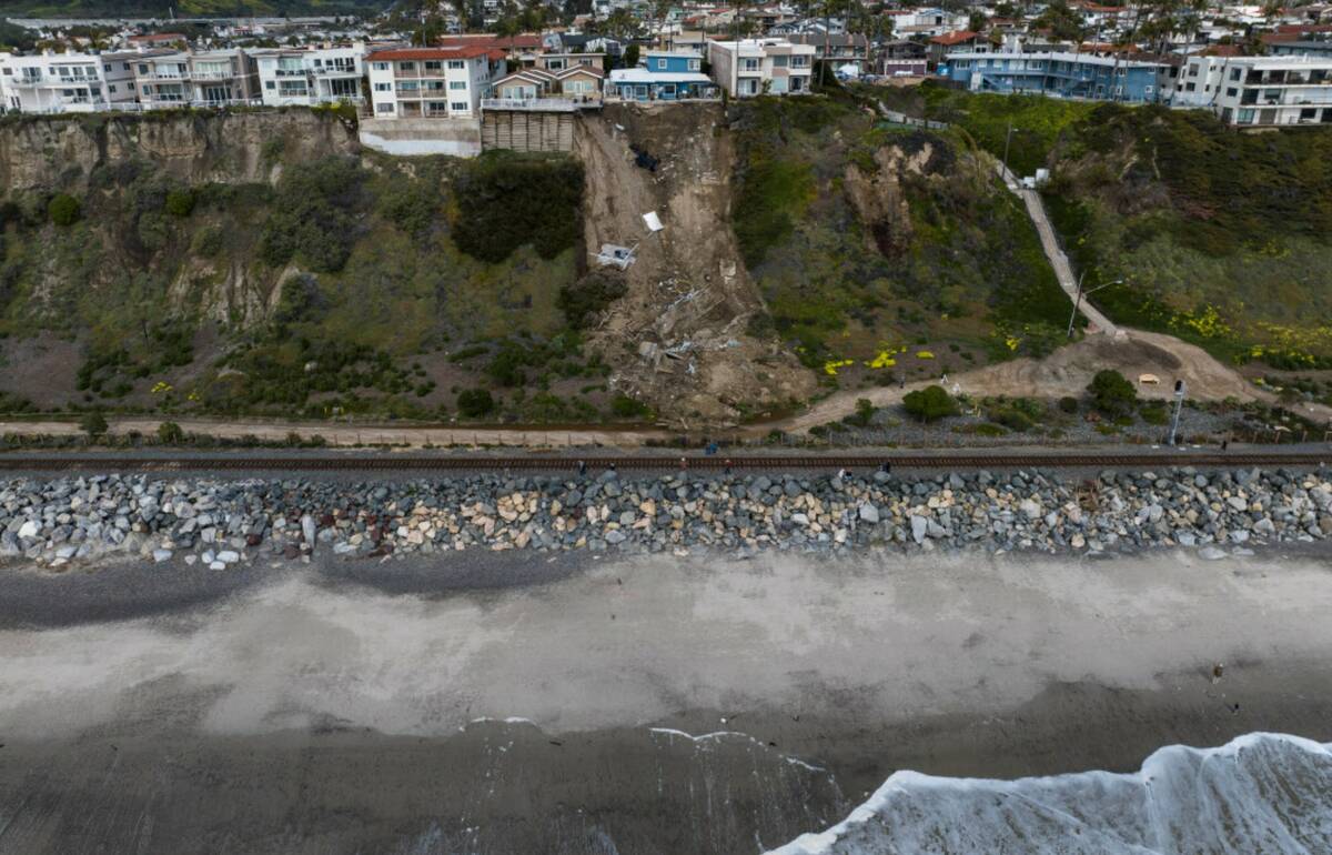 In this image taken with a drone, a mass of debris is seen along a cliff beneath residential ho ...