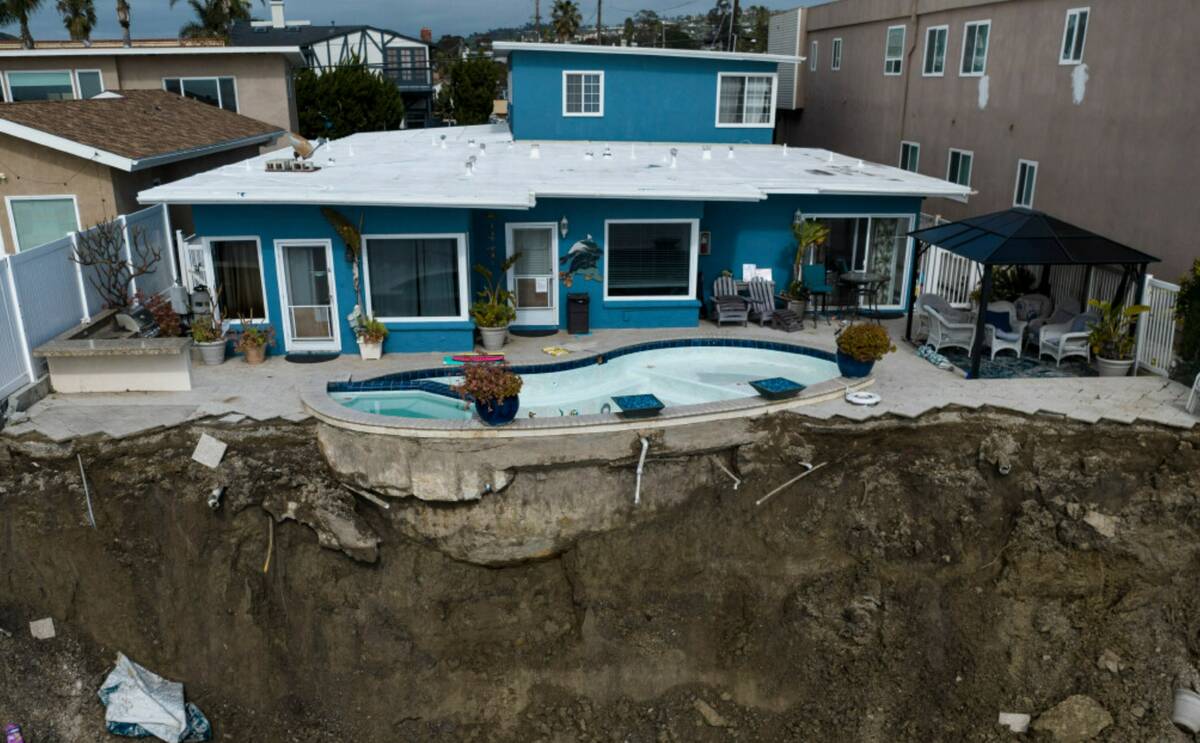 In this image taken with a drone, a residential swimming pool hangs on a cliffside after a land ...
