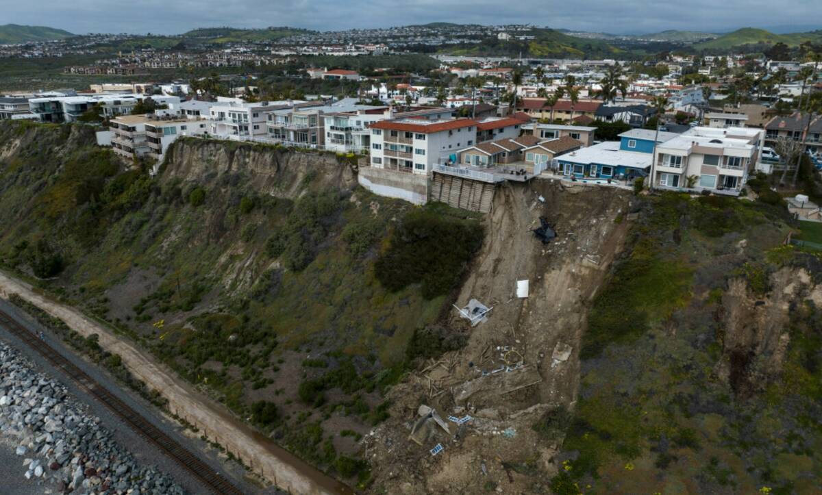 In this image taken with a drone, a mass of debris is seen along a cliff beneath residential ho ...