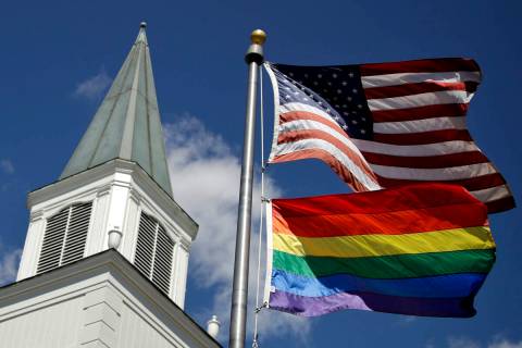 A gay pride rainbow flag flies along with the U.S. flag in front of the Asbury United Methodist ...