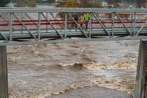 People cross a bridge over a swollen Los Angeles River in Los Angeles on Saturday, Jan. 14, 202 ...