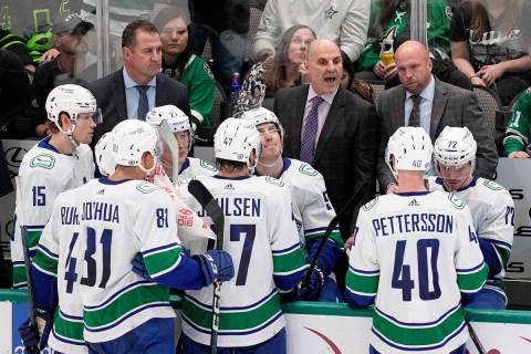 Vancouver Canucks head coach Rick Tocchet, top center, instructs his team during a timeout in t ...