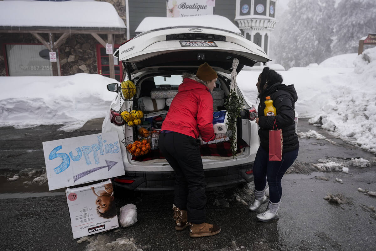Ruth Aldama, center, who set up a makeshift supply shop on the road, talks to a resident in Run ...