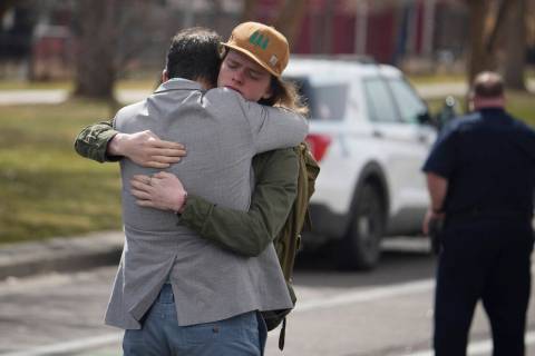 A student, right, hugs a man after a school shooting at East High School Wednesday, March 22, 2 ...