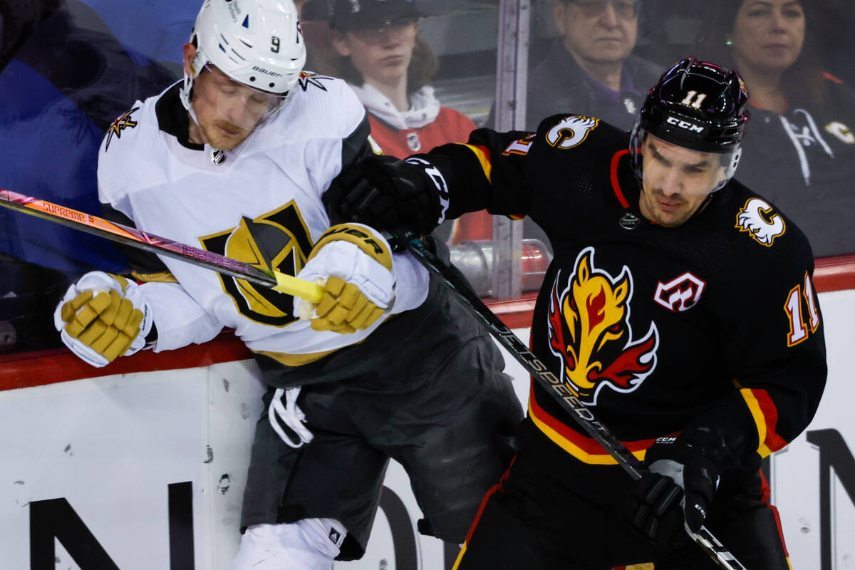 Vegas Golden Knights forward Jack Eichel, left, is checked by Calgary Flames forward Mikael Bac ...