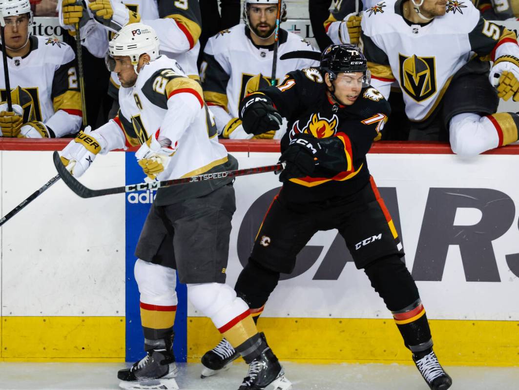 Vegas Golden Knights defenseman Alec Martinez, left, checks Calgary Flames forward Walker Duehr ...