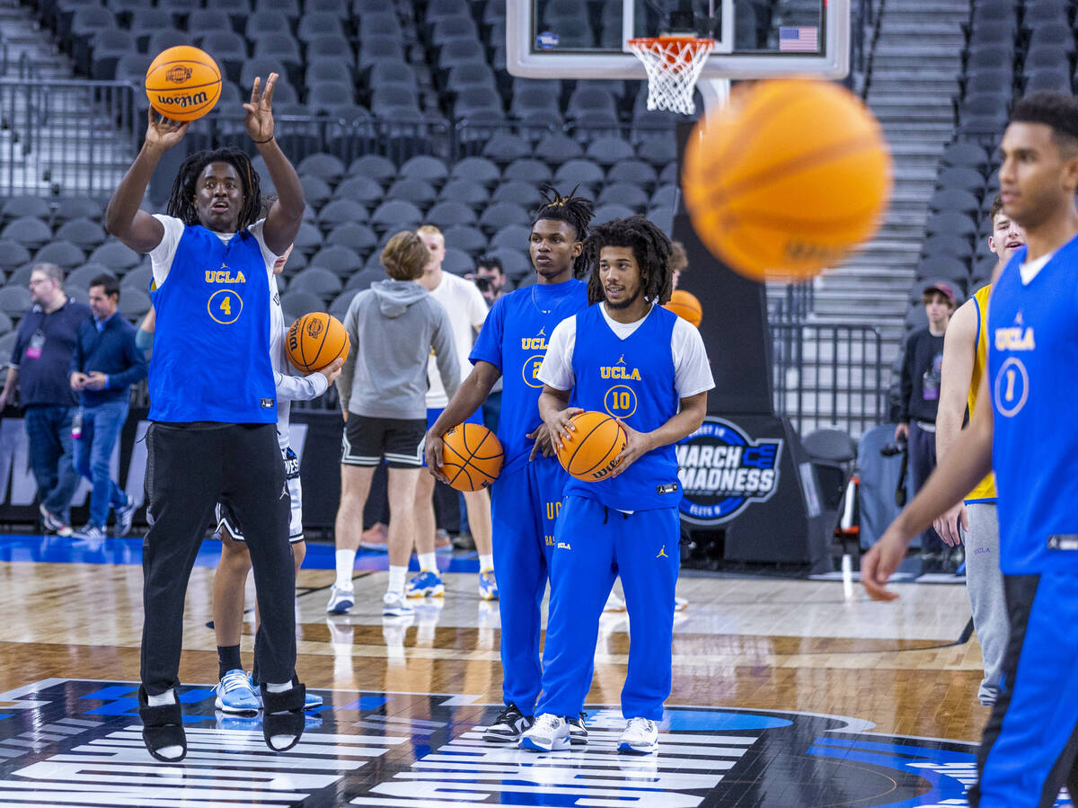 UCLA guard Will McClendon, left, releases a half-court shot as players gather on the court dur ...