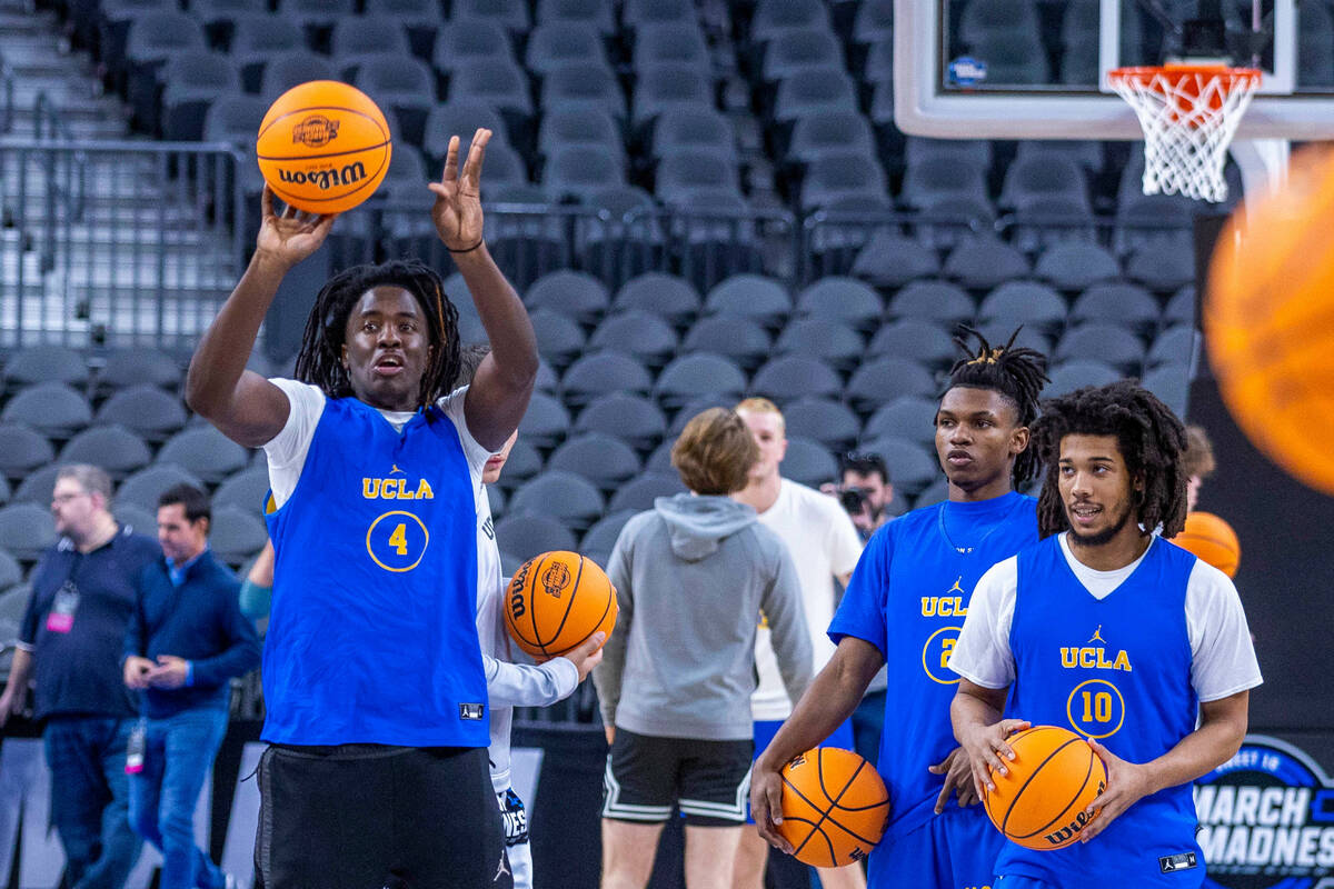UCLA guard Will McClendon, left, releases a half-court shot as players gather on the court dur ...