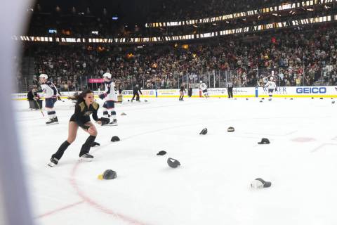 A member of the Golden Knights ice crew picks up hats after center Jack Eichel, not pictured, l ...