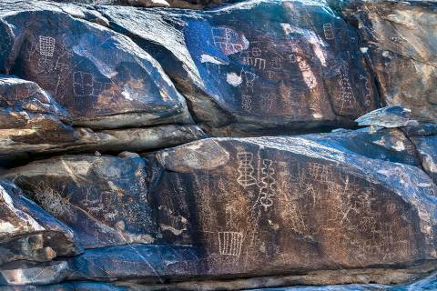 Native American petroglyphs line the rock walls along the canyon bottom in Hiko Springs within ...