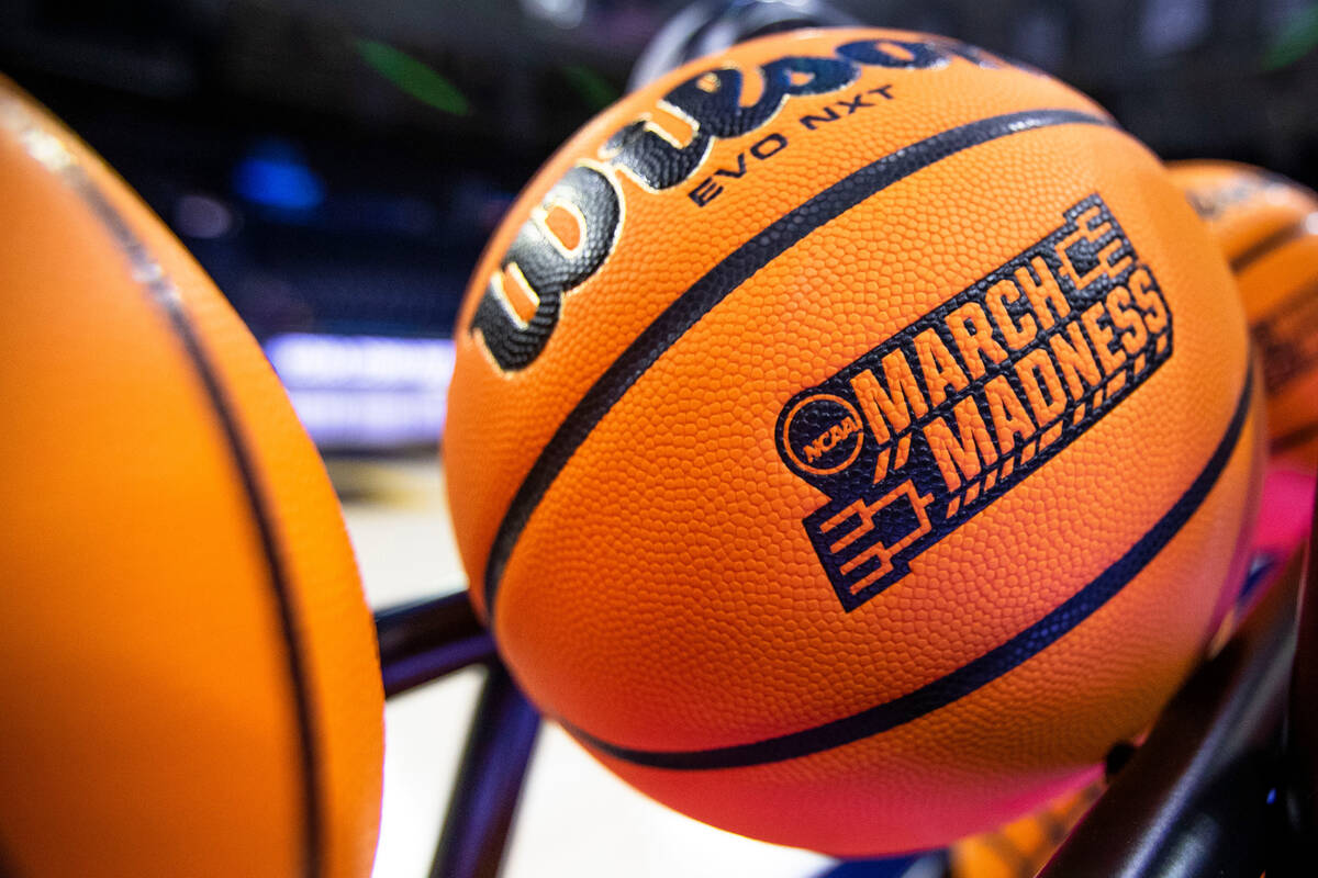 FILE - A basketball with a March Madness logo rests on a rack before a First Four game between ...