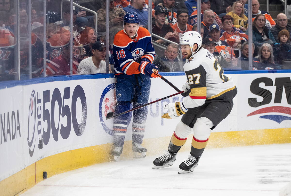 Vegas Golden Knights' Shea Theodore (27) and Edmonton Oilers' Zach Hyman (18) compete for the p ...