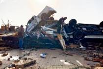 Law-enforcement officers climb through debris on a diner looking for survivors early Saturday, ...